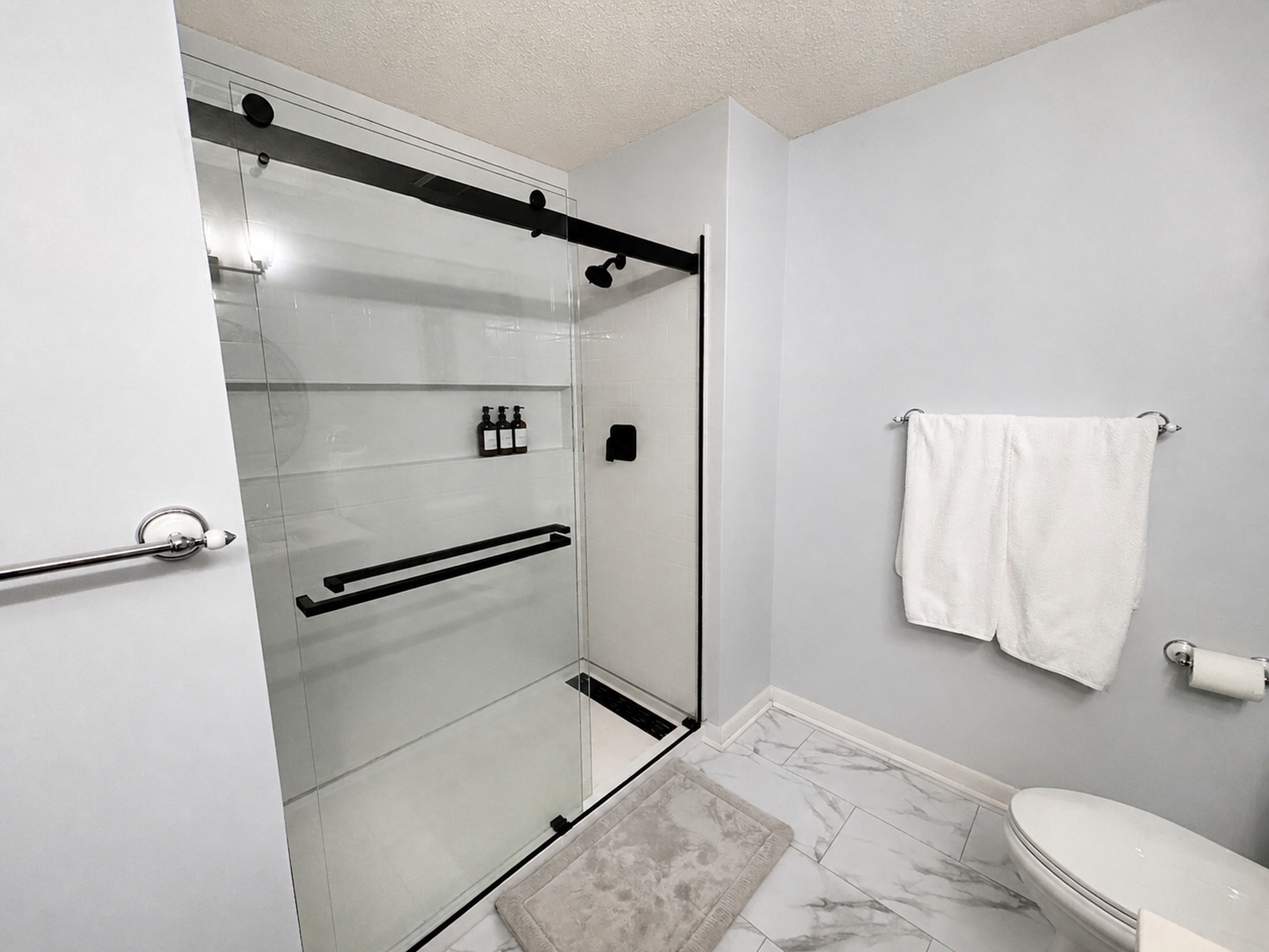 Walk-in glass shower with black hardware in a Beaches Be Salty bathroom