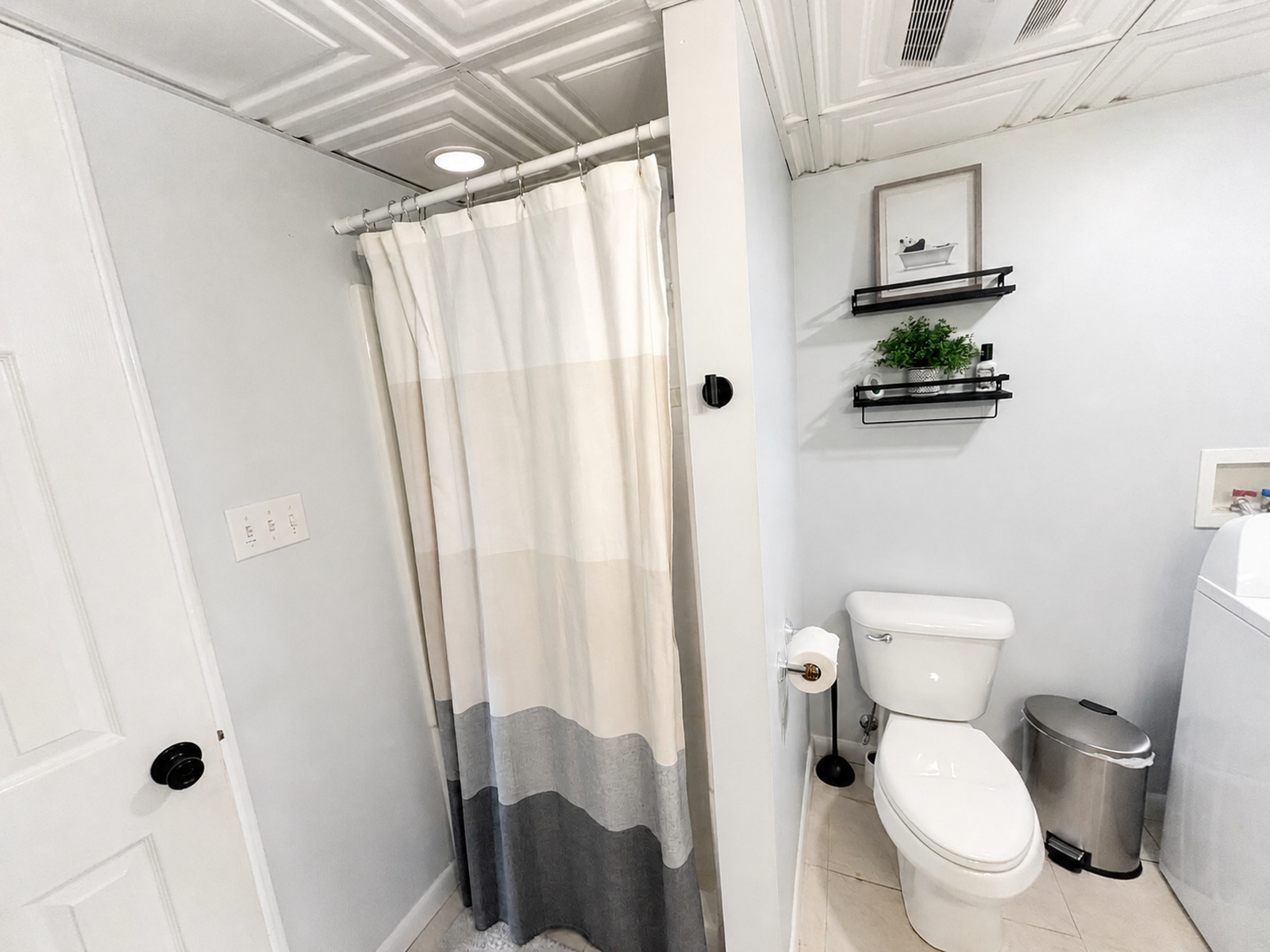 Full bathroom at Beaches Be Salty with shower curtain, toilet, and decorative wall shelves