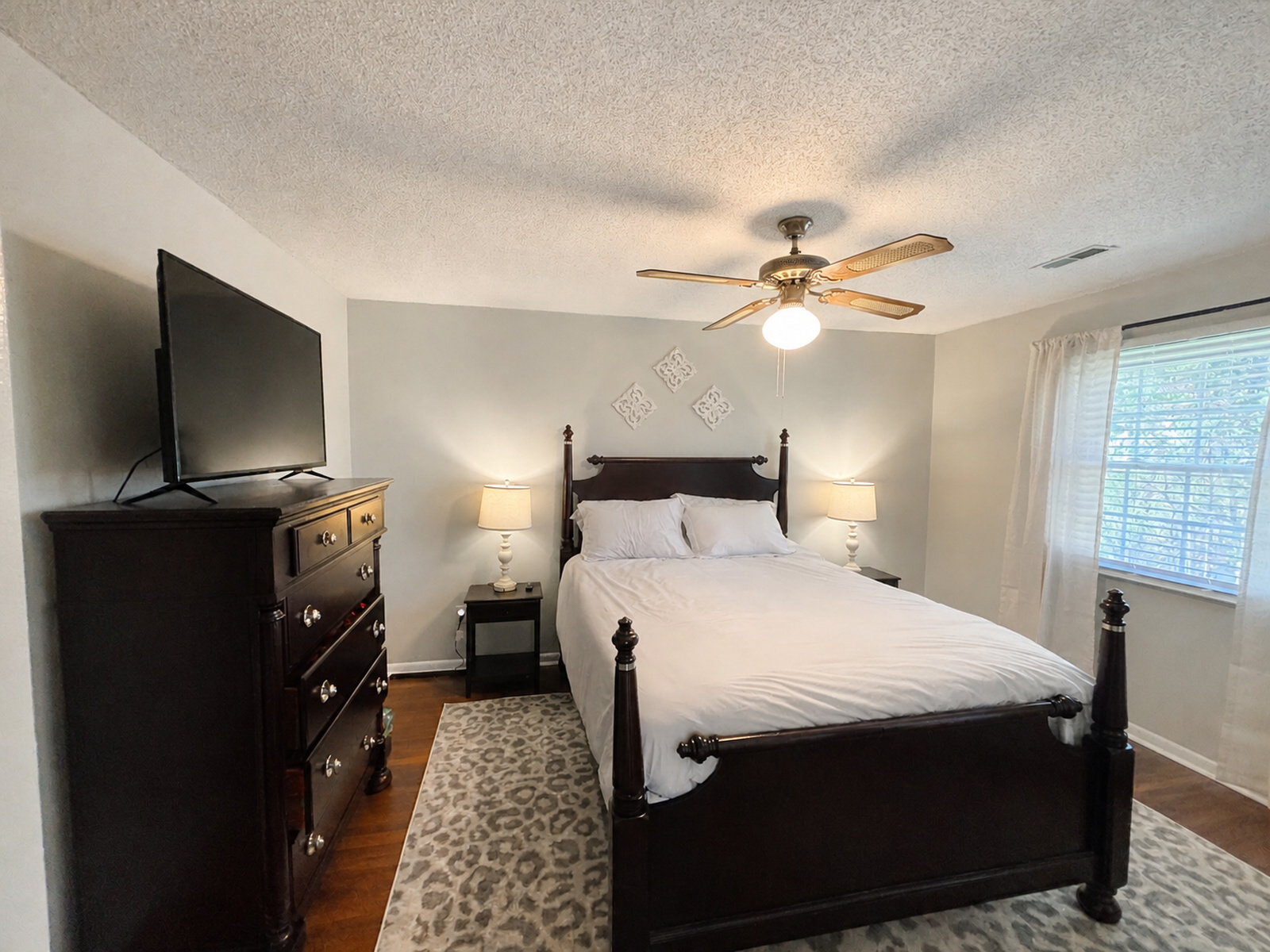 Main-level king bedroom at Beaches Be Salty with ceiling fan, dresser, and two windows