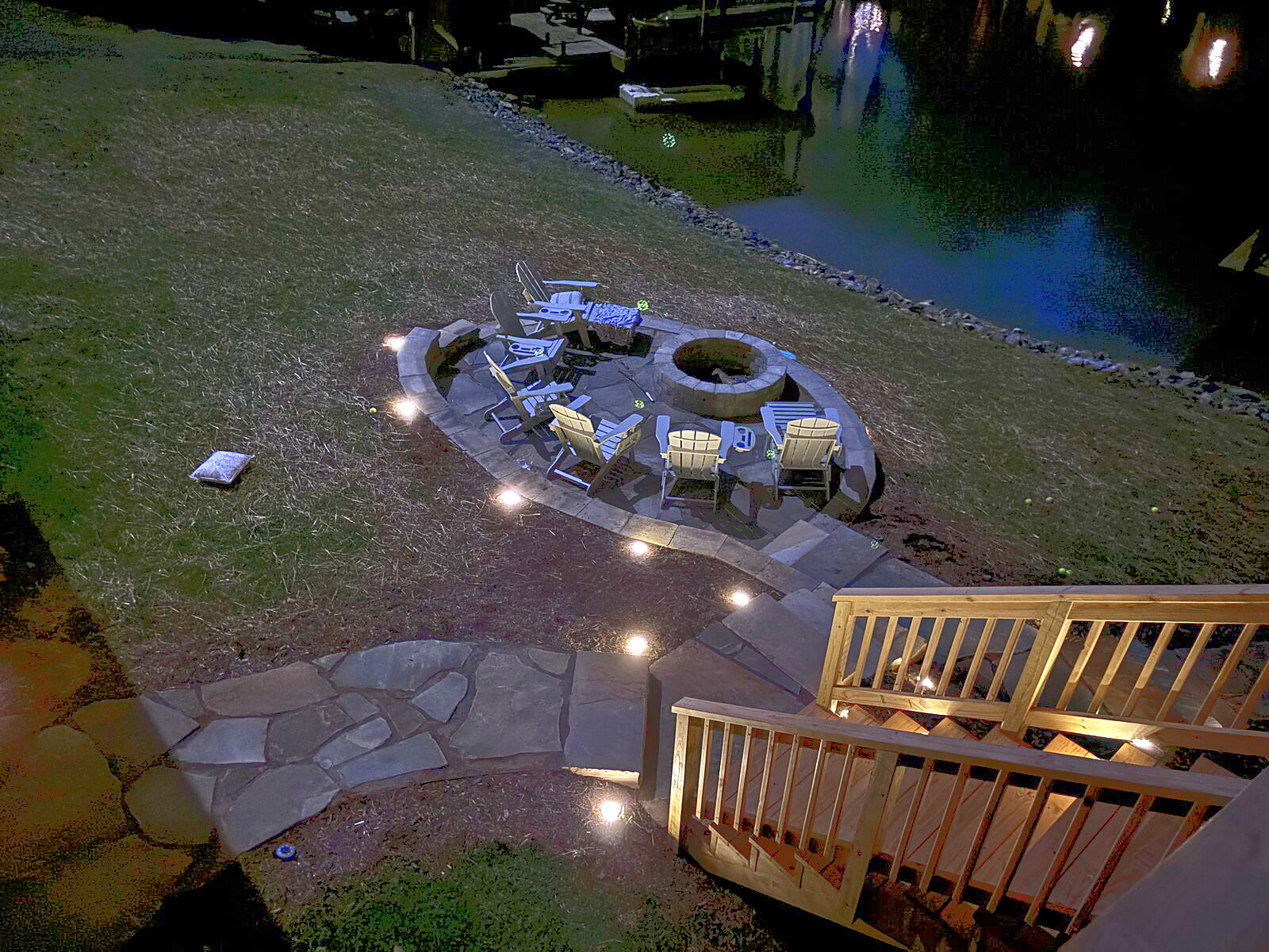 Lakeside fire-pit patio and illuminated steps at Beaches Be Salty after dark