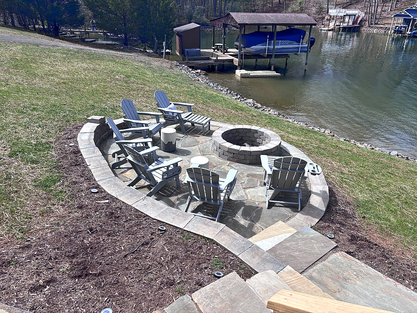 Stone fire-pit patio with Adirondack chairs beside Smith Mountain Lake at Beaches Be Salty
